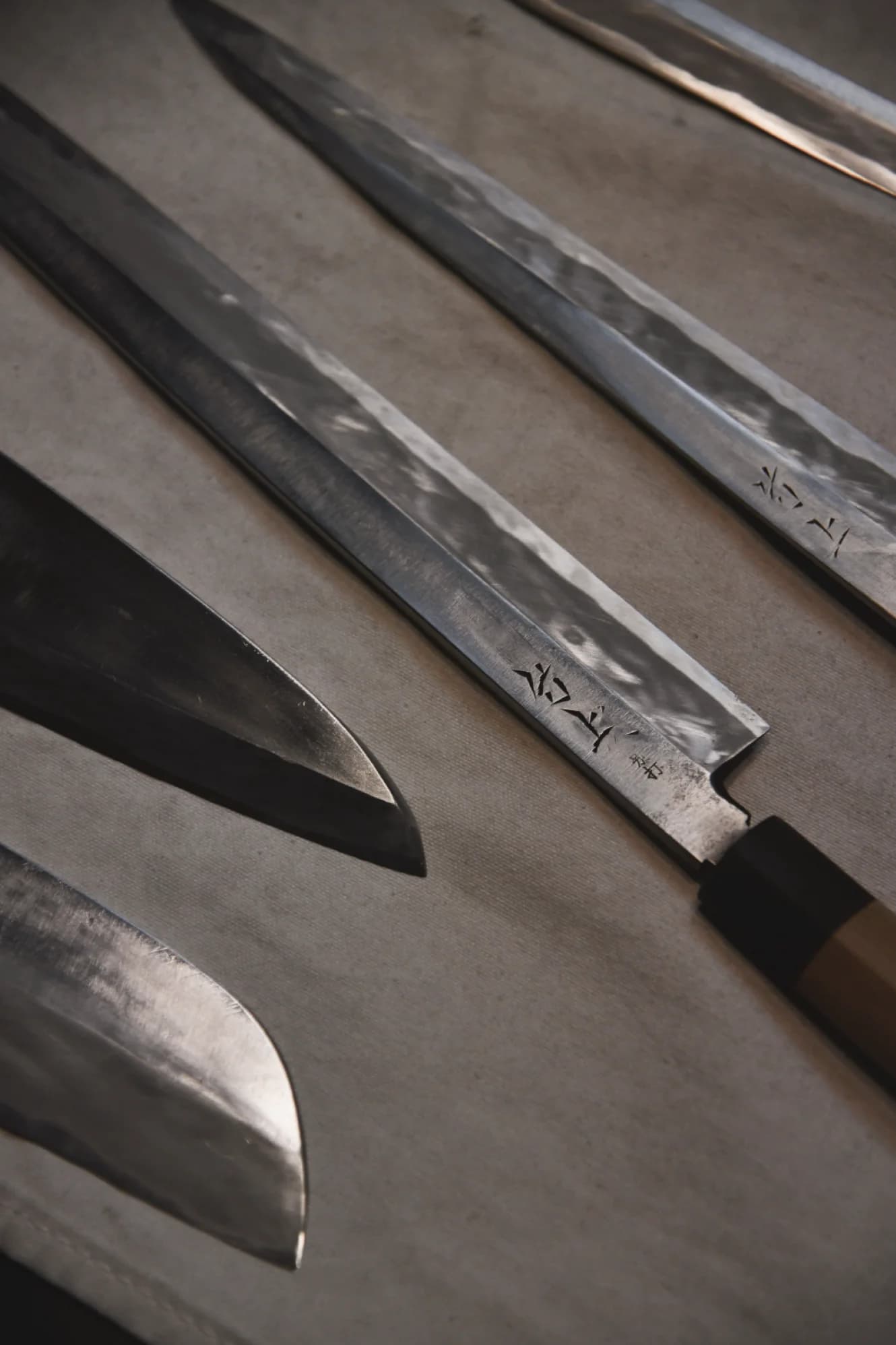 Close-up of traditional Japanese knives with dark textured blades and wooden handles
