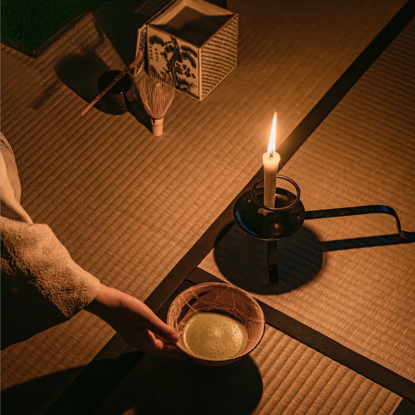 Bowl of tea on a tatami mat with candle and tea set