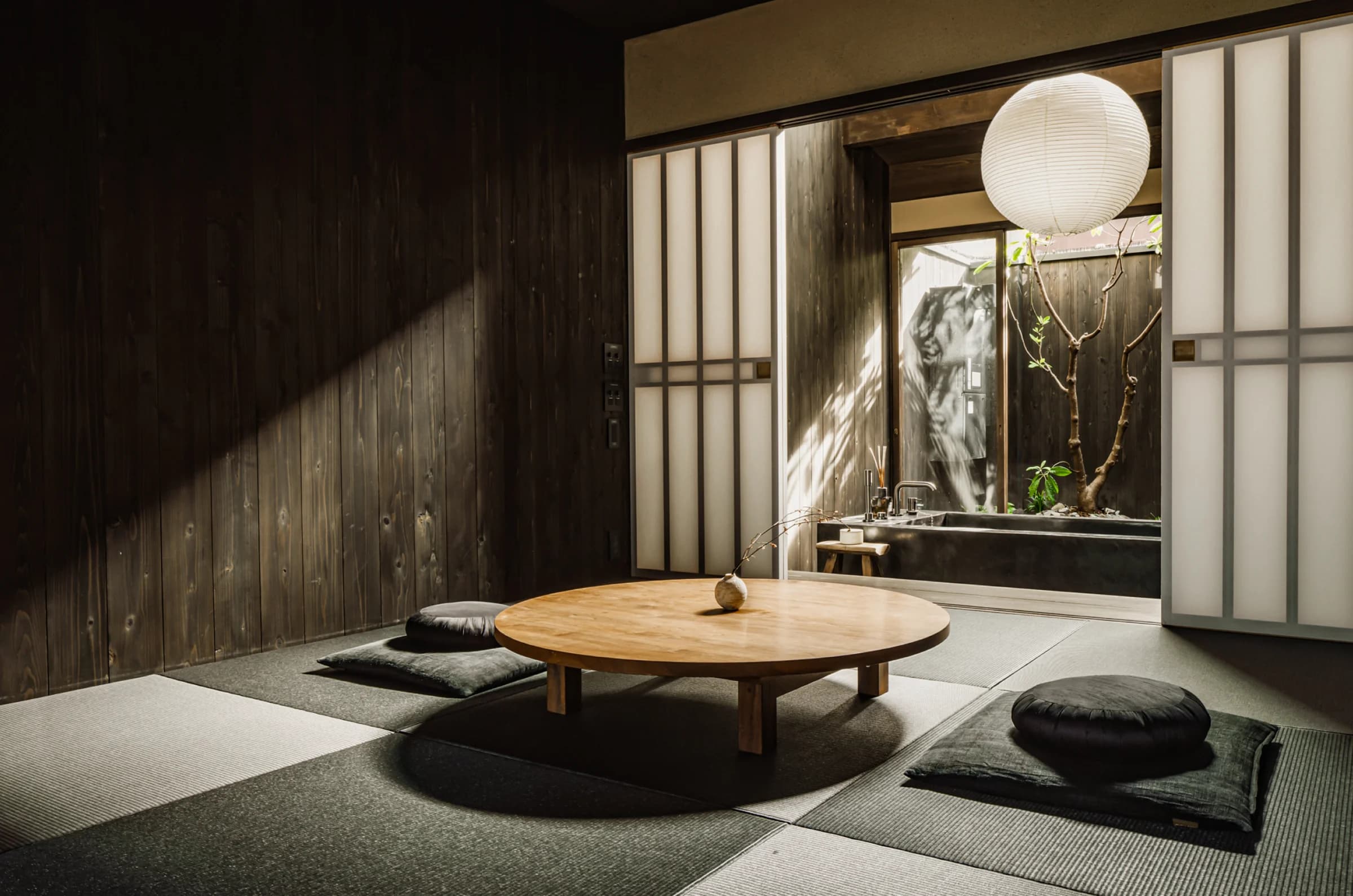 Tatami living room with round wooden table, floor cushions, and paper lantern