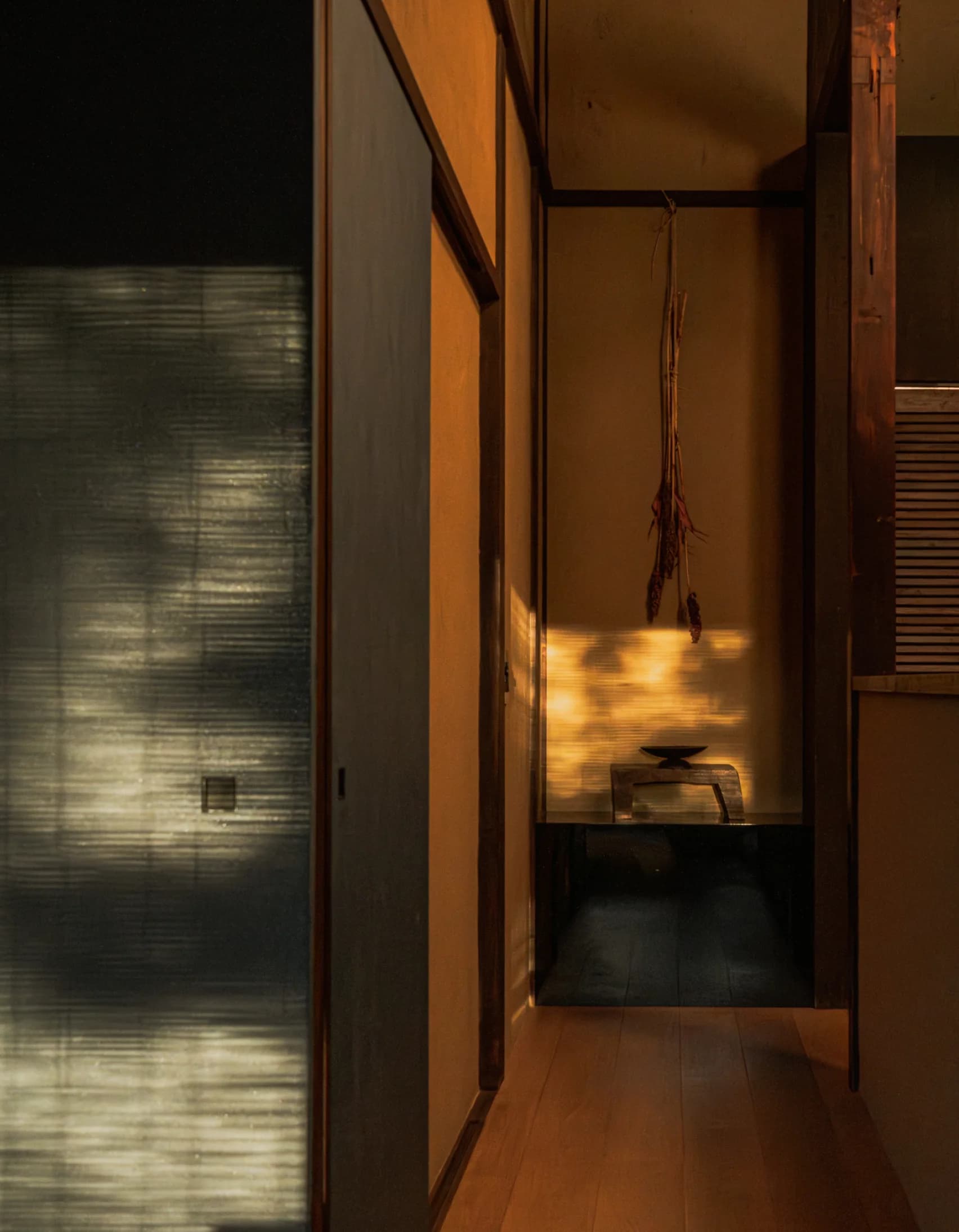 Dimly lit wooden hallway with warm overhead light and plastered walls